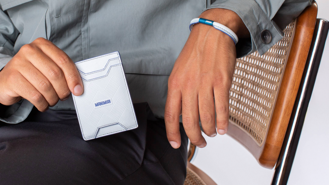 Stylish guy holding a MANIMIRI Ice Blue Spring card holder and wearing the bracelet from the same collection in a photo studio.