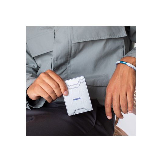 Stylish guy holding a MANIMIRI Spring card holder in light blue while wearing the bracelet in the same color