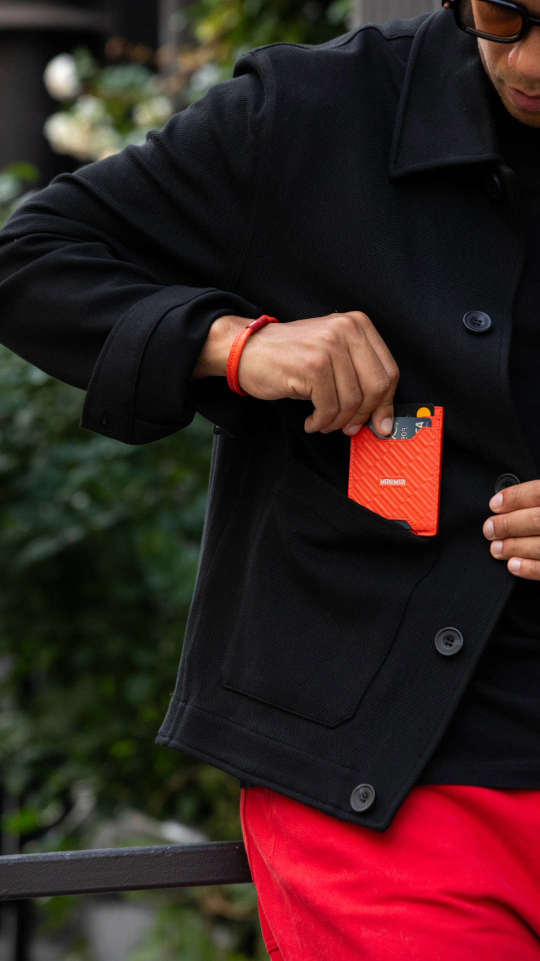 Stylish guy holding a MANIMIRI Spring card holder and bracelet in Orange in Soho NYC